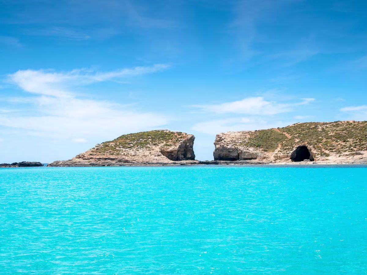 Bright turquoise water between Comino and the smaller island of Cominotto, with rocky shores and caves.