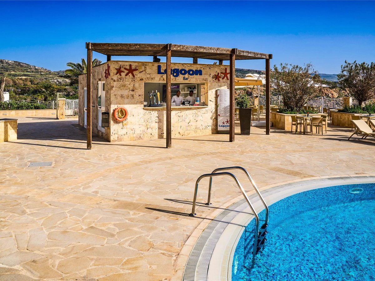 Stone bar kiosk under a timber pergola with Lagoon Bar lettering and red starfish motifs, two staff at the counter and a pool in the foreground.