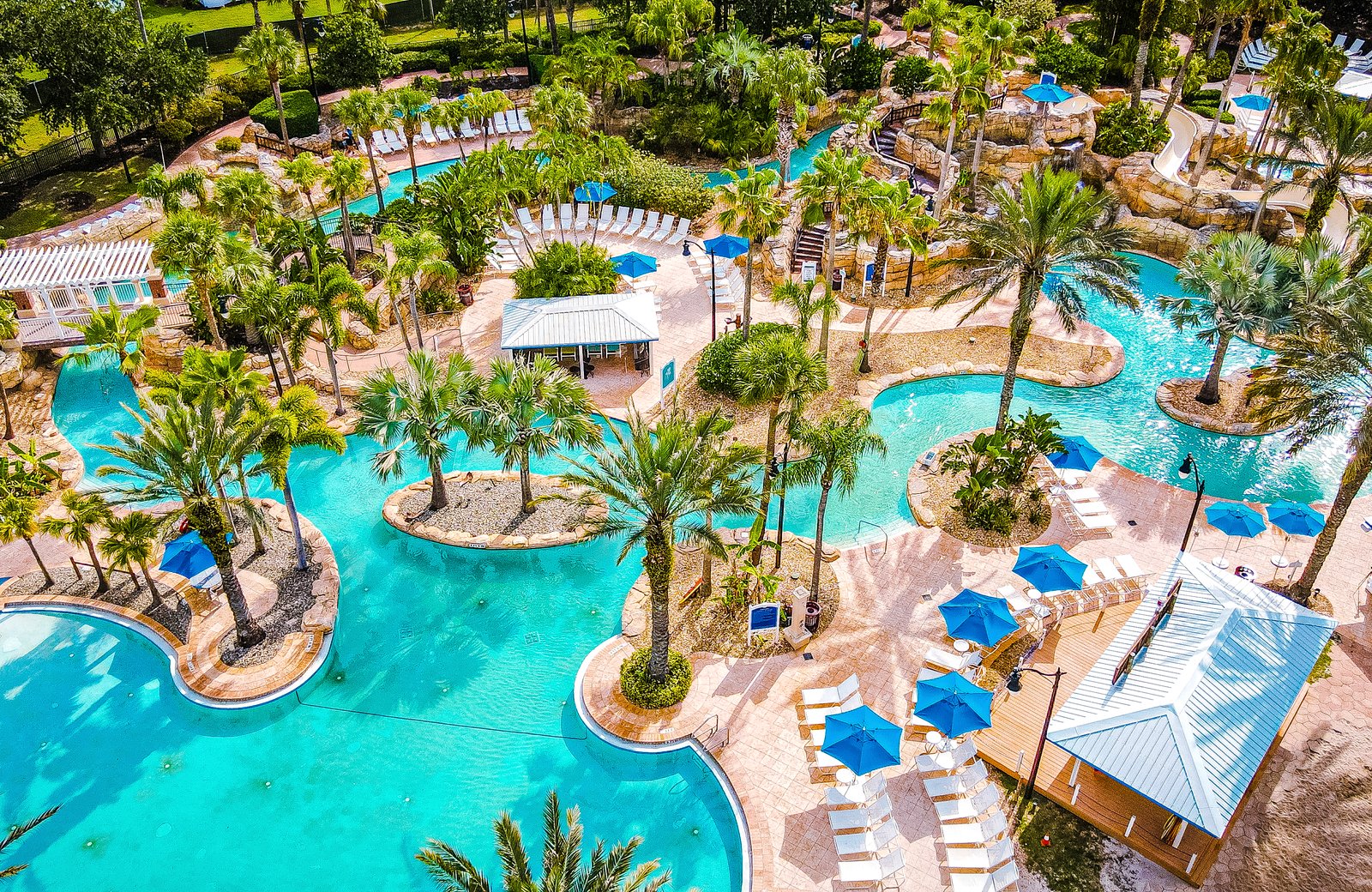 An aerial view of Reunion Resort's five-acre water park, its winding lazy river and pools threading between palm-planted islands, sun loungers and parasols all around.