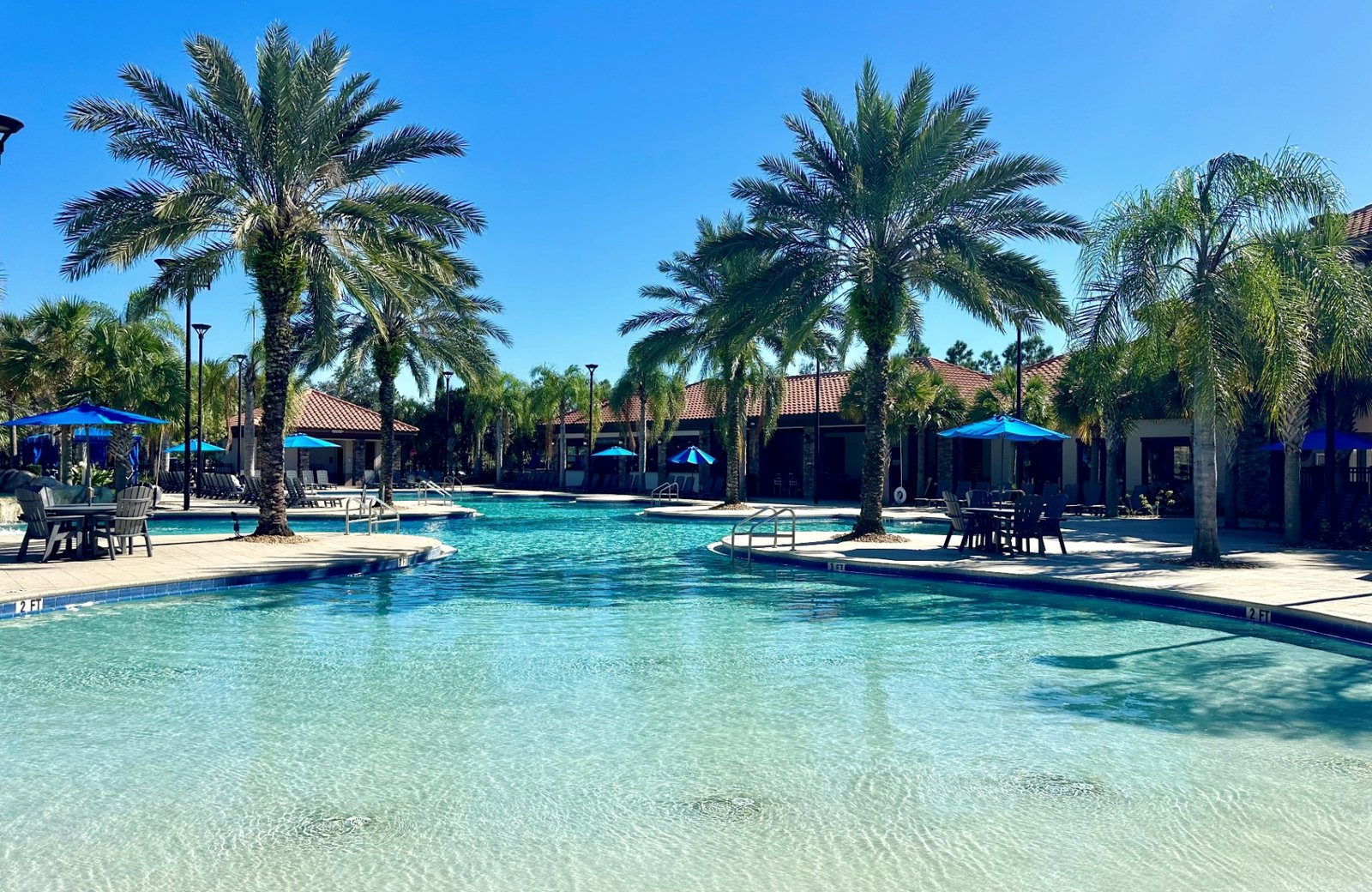 Solterra Resort: the large zero-entry clubhouse pool sloping in like a beach, with sun loungers and palms around it and the cream Mediterranean-style clubhouse behind.