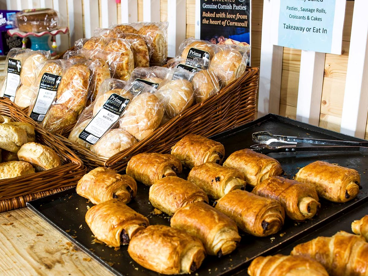 Trays of pains au chocolat and baskets of bread rolls and pasties on a bakery counter.