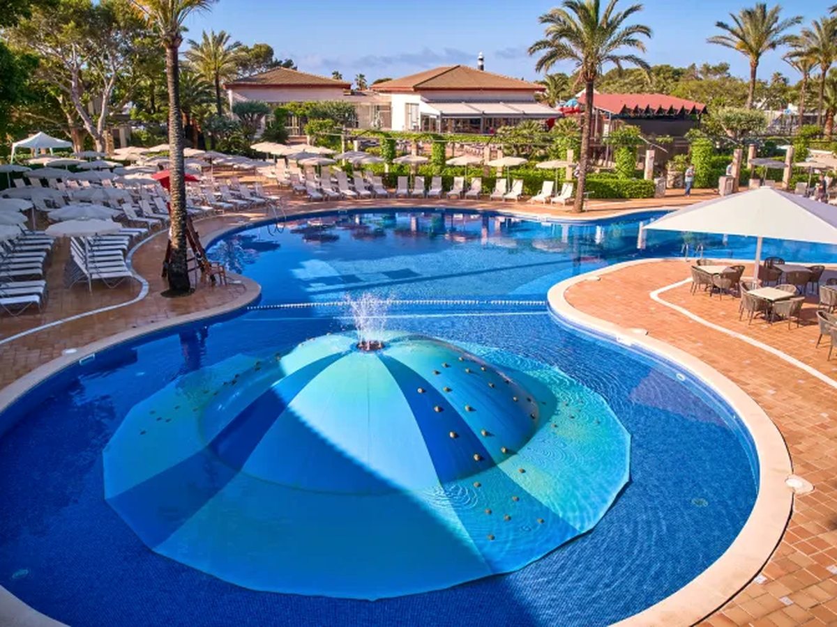 A large blue dome-shaped water feature with jets in a shallow round section of the pool, with sunbeds and parasols around the terrace.