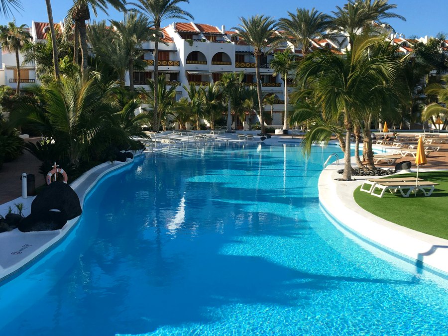 A Los Cristianos resort pool, with palms and low-rise apartments behind